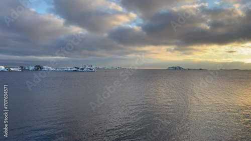 Calm winter coast in Norway, captured in smooth slow motion and 4K clarity. Snow meets blue water in a simple, peaceful scene. Low sun. photo