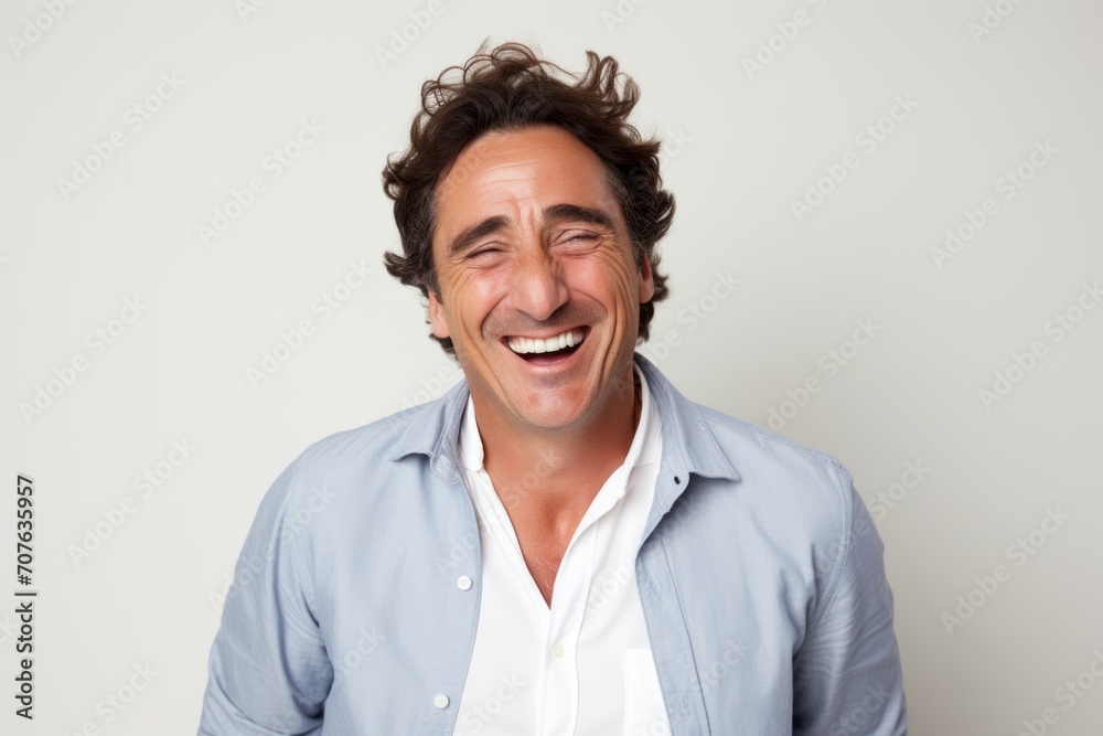 Portrait of happy man laughing and looking at camera against white background