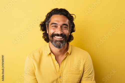 Portrait of happy bearded Indian man in yellow shirt on yellow background © Inigo