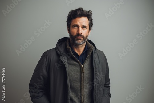 Handsome bearded man in a black jacket on a gray background
