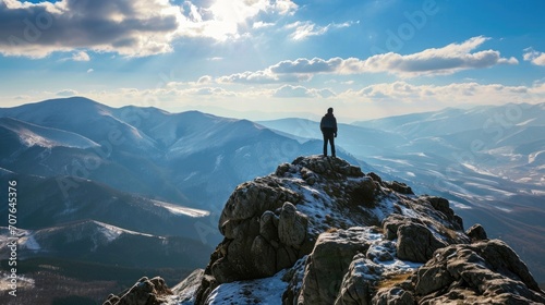 Hiker standing on a mountain peak overlooking a range.