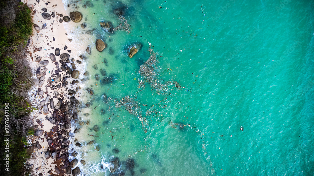 Aerial view of a tropical beach with crystal-clear water, sandy shore, and scattered rocks, depicting a serene vacation destination