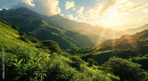 Sunrise over lush green mountains with light rays piercing through the foliage.