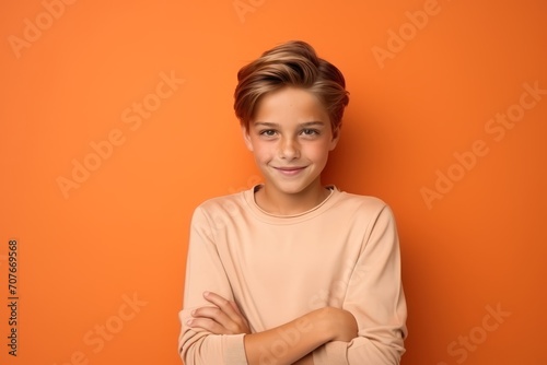 Portrait of a cute little boy with folded arms on orange background