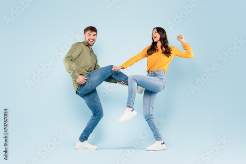Playful couple dancing and laughing on blue background