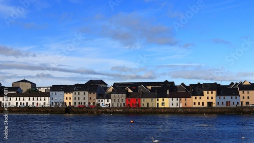 Vibrant array of houses in various bold colors, dotting the shoreline in Galway Ireland.