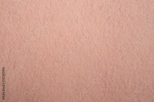 Felt fabric texture with visible fiber, peach pink color abstract pattern backdrop, close up