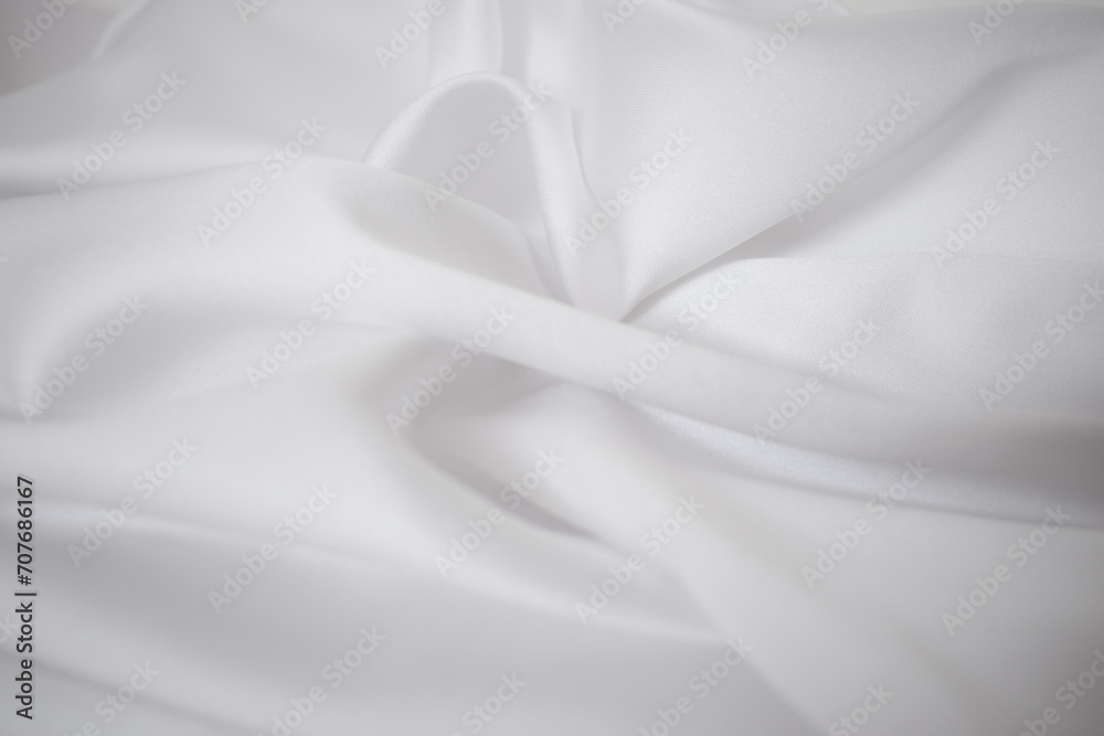 Abstract white satin fabric texture background. Soft cloth  waves and creases of  silky drapes. Soft focus close up