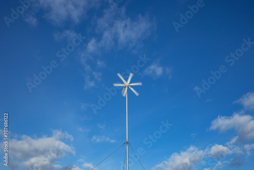 Domestic wind mill spinning against blue sky, motion blur present