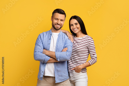 Portrait of happy young european couple posing over yellow studio background photo