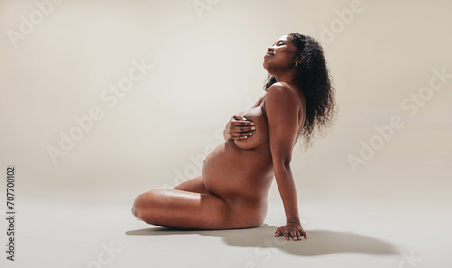 Black mother-to-be embracing her beautiful and naked pregnancy body photo