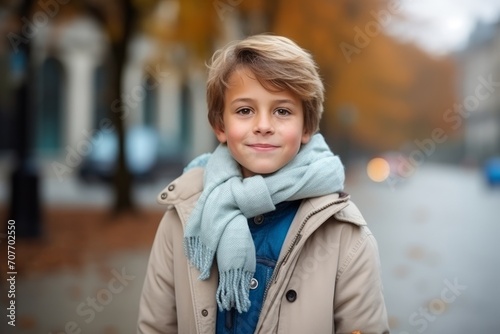 Outdoor portrait of cute little boy in coat and scarf looking at camera