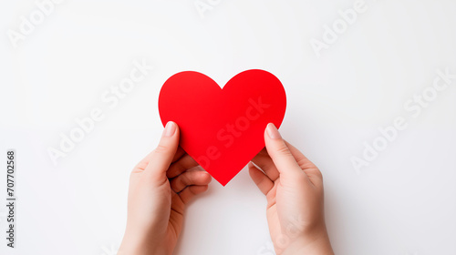 Female hands holding a paper red heart on white background with copy space. love, health care, world mental health day, organ donation,