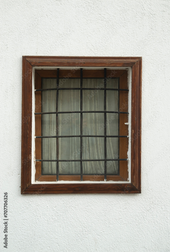 Old small wooden window with metal grill and curtain on facade Old small wooden window with metal grill and curtain on facade