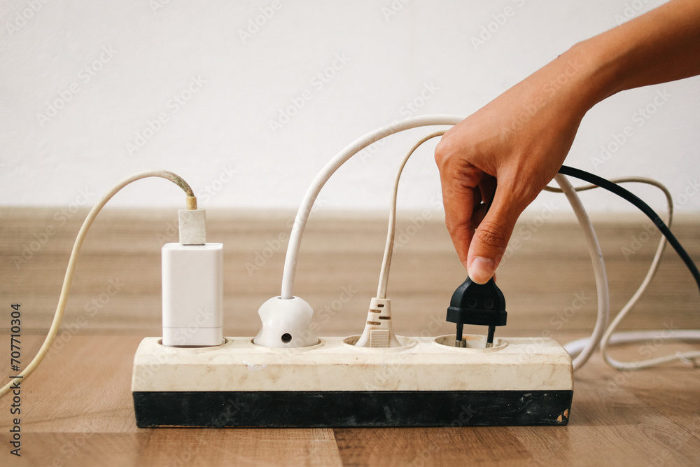 Hand holding electric plug put on multiple socket. Electrical appliances plugs full of all plugs. Hand holding electric plug put on multiple socket. Electrical appliances plugs full of all plugs.