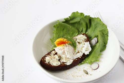 Toast with Cream Cheese, Poached Egg, Seasoning with Black Pepper, Seeds on Plate with Salad Leaves and Radish Slices. Delicious Breakfast, Lunch.