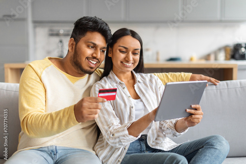 Online Shopping Concept. Smiling Indian Couple Using Digital Tablet And Credit Card