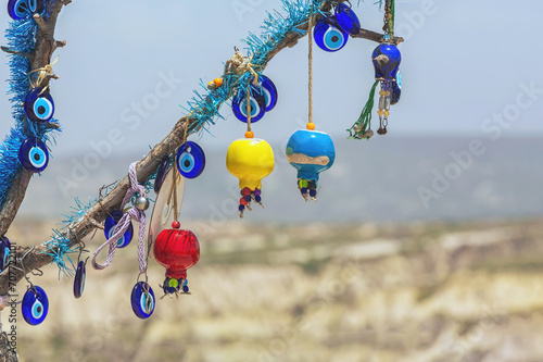 Colorful ceramic pomegranates and evil eye amulets on pendant on tree brunch. Cappadocia defocused landscape at background. Traditional gift or souvenir from Turkey. Copy space. Uchisar (Cappadocia)