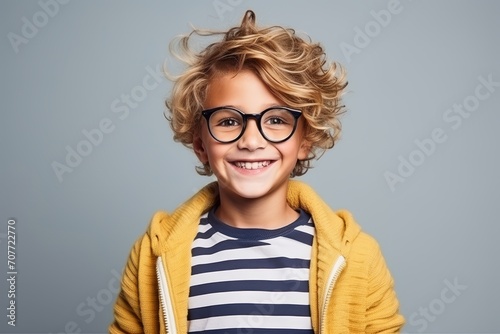 Portrait of a cute little boy in glasses over grey background.