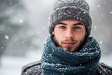 Studio portrait of a young European man with a winter theme, wearing a scarf and beanie, isolated on a snowy background