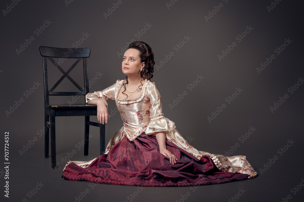 Φωτογραφία Young beautiful serious woman in medieval style dress sitting on the floor near