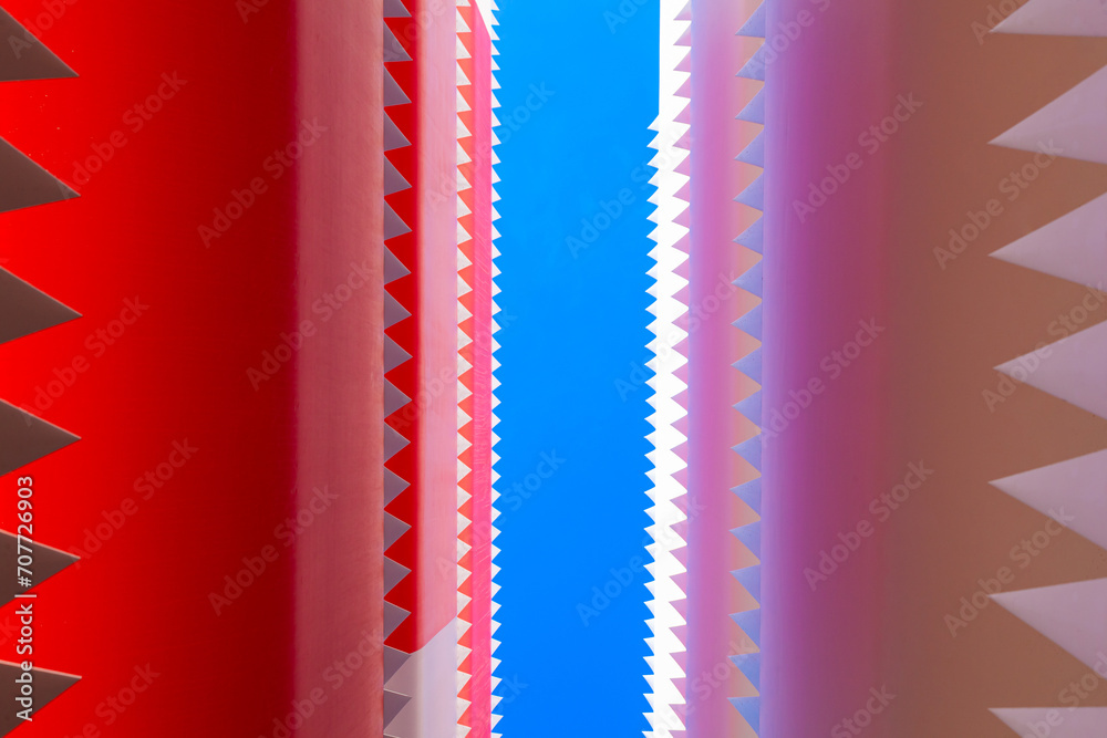 Jagged edges of folded wind turbine blades against a blue background, bottom view.