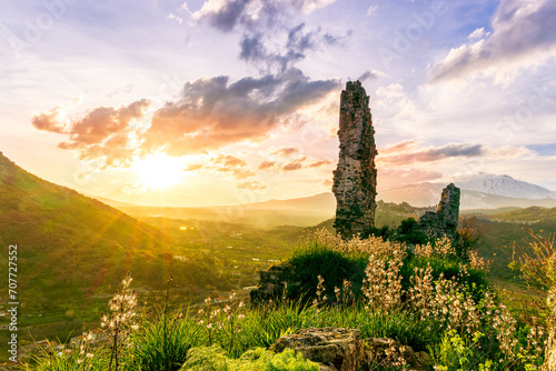 beautiful medieval castle ruins on mountain during nice sunset or sunrise with highland landscape on background