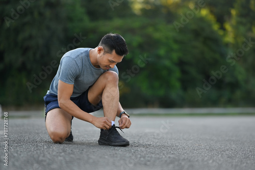 Young sportsman tying shoelace ready for morning jogging. Workout and healthy lifestyle concept