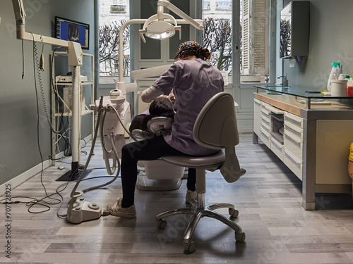 Dentista concentrada a tratar uma paciente no seu consultório photo