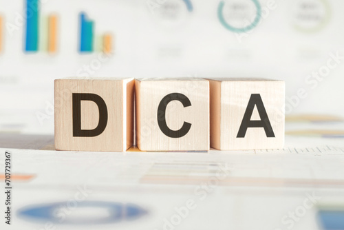 DCA symbol (Dollar-Cost Averaging) from wooden Cube, Signifying a Methodical Approach to Building Wealth Over Time.