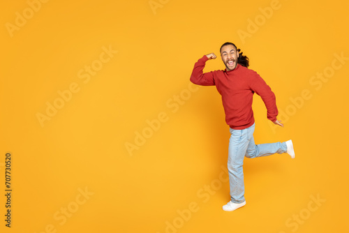 Excited young man clenching fist and running