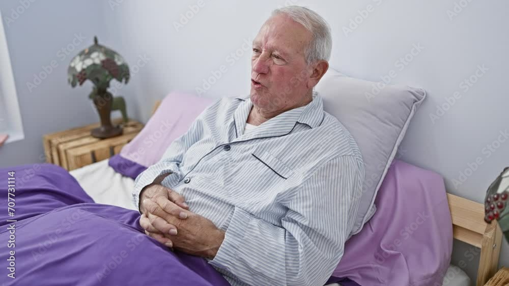 Upset senior man in pyjamas frowning skeptically on bed, displaying negative emotion due to a problem. nervous character portrayal in bedroom setting. Upset senior man in pyjamas frowning skeptically on bed, displaying negative emotion due to a problem. nervous character portrayal in bedroom setting.