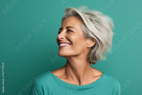 Happy mature woman with closed eyes and white hair on turquoise background