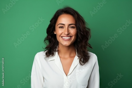 Portrait of a happy young businesswoman smiling at camera against green background © Iigo