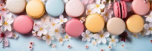Colorful french desserts with spring flowers, top view, flat lay. Cake macaroons on plain background, colorful almond cookies, spring flowers, pastel colors. Banner. Flat lay, top view