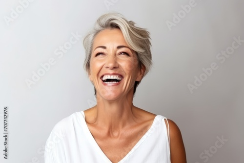 Portrait of a happy senior woman laughing against grey background with copy space