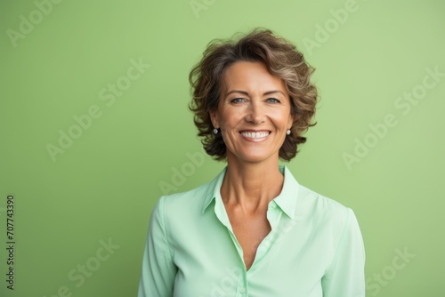 Portrait of smiling middle aged businesswoman looking at camera against green background