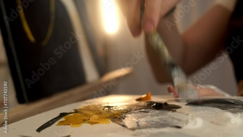 Closeup woman female hand artist painter paints draws creating new art work on canvas in workshop lesson of painting enjoying process of drawing creating picture using brush applying oil paint palette photo