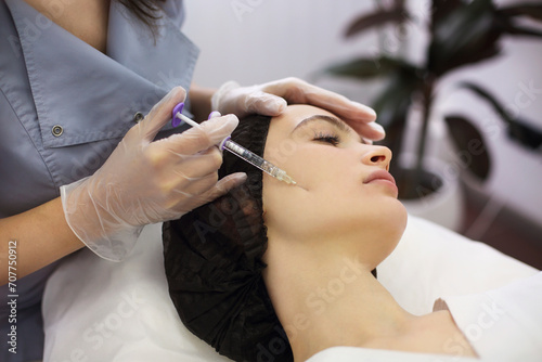 Beautician injecting woman face at beauty salon