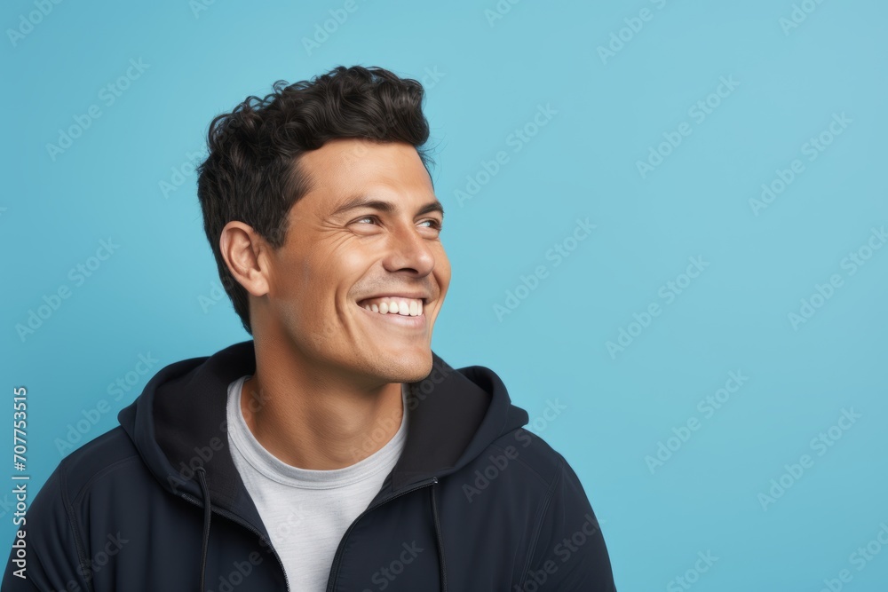 Portrait of a happy young man smiling and looking away against blue background Portrait of a happy young man smiling and looking away against blue background