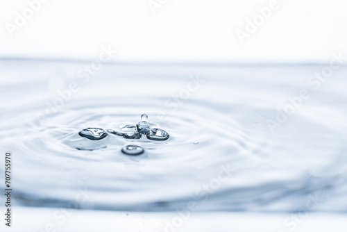 Captivating water droplet creating intriguing shapes  generating movement  bubbles  and splashes on a pristine white background. Ideal for banners promoting purity  freshness  and vitality.
