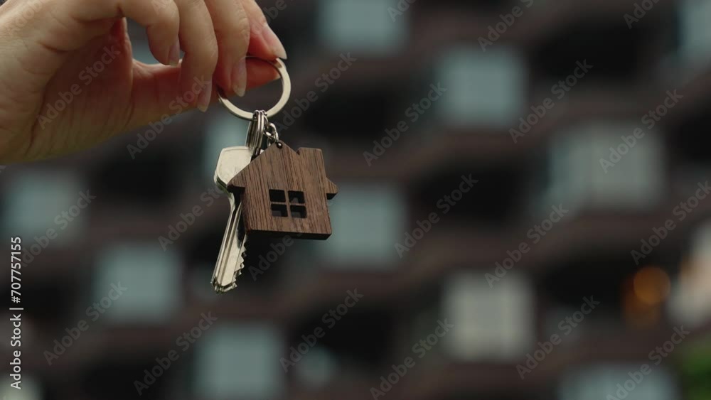 Hand holding a key against the background of an apartment building. The concept of a new home, business, investment and real estate Hand holding a key against the background of an apartment building. The concept of a new home, business, investment and real estate