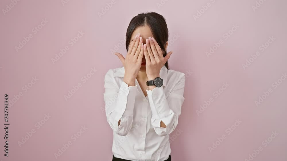Shocked young chinese woman, afraid yet curious, timidly peeks through her shy fingers. wearing glasses, standing over vibrant isolated pink background, she covers her face in surprise. Shocked young chinese woman, afraid yet curious, timidly peeks through her shy fingers. wearing glasses, standing over vibrant isolated pink background, she covers her face in surprise.