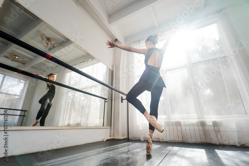 A beautiful Asian woman is dancing at the barre. Ballet dancer.