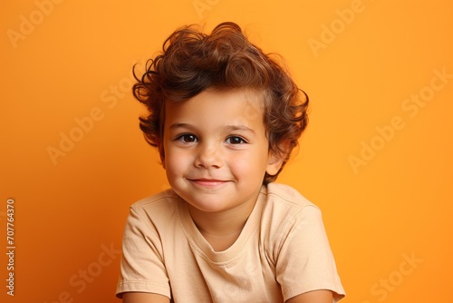 Portrait of a cute little girl with curly hair on orange background