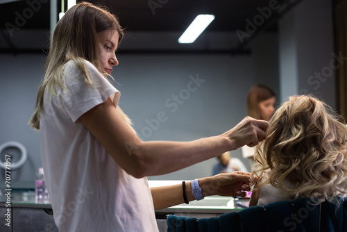 Barber woman make curly hair fashionable hairdo for lovely girl in barber shop at mirror. Hairdresser lady combing for cute kid, haircare. Customer service at hair salon concept. Copy ad text space