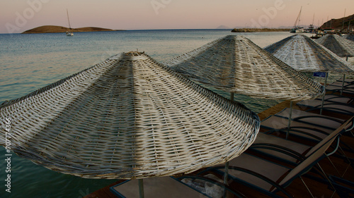Fototapeta Naklejka Na Ścianę i Meble -  Aegean and Mediterranean coasts at sunset. Wicker umbrellas and sun loungers. Beach restaurants. Palamutbuku beaches of Mugla, Turkiye.