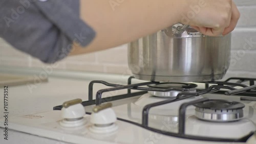 Woman Put The Pot And Presses The Rotary Switch To Turn On Gas Stove. photo