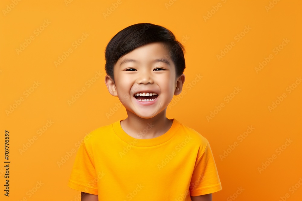 a professional portrait studio photo of a cute asian boy child model with perfect clean teeth laughing and smiling. isolated on orange background. for ads and web design a professional portrait studio photo of a cute asian boy child model with perfect clean teeth laughing and smiling. isolated on orange background. for ads and web design
