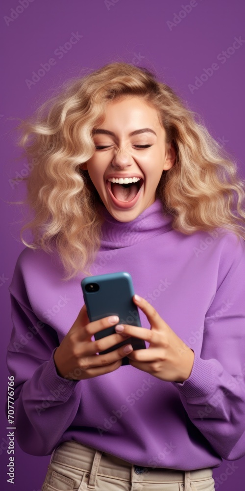 Excited girl with smartphone Happy student customer using mobile phone to celebrate on vertical purple background Excited girl with smartphone Happy student customer using mobile phone to celebrate on vertical purple background